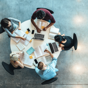 Image of a group of people sitting around a table working on laptops