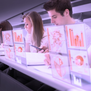 Image of a man and woman sitting next to each other in front of computer screens with imagery on them. 