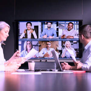 Image of people meeting around a table while talking to people on a screen during a training