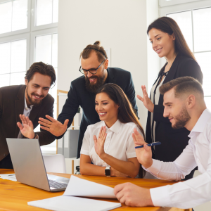 Group of people working together and talking to a laptop